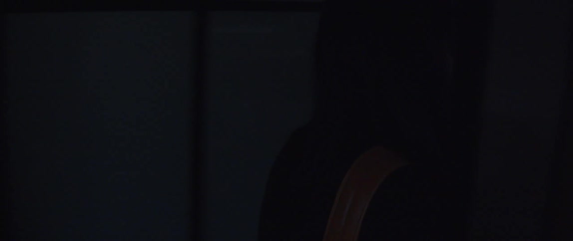 A woman is standing in a room speaking to someone and she turns and walks around a desk and down the hallway