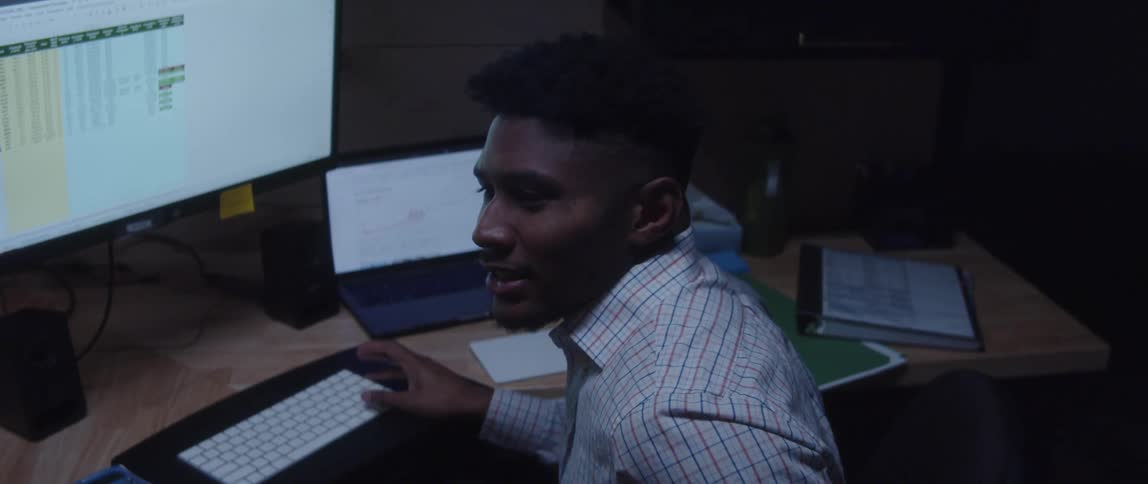 A man sitting at his desk talking to someone and looking stressed