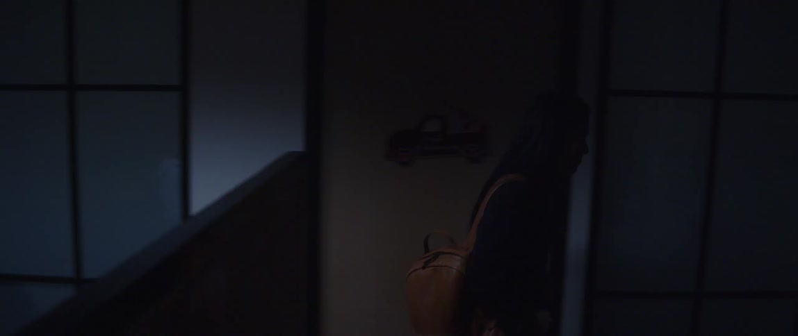 A woman leaning over and speaking to a man at his desk and then walking away from the office toward the door