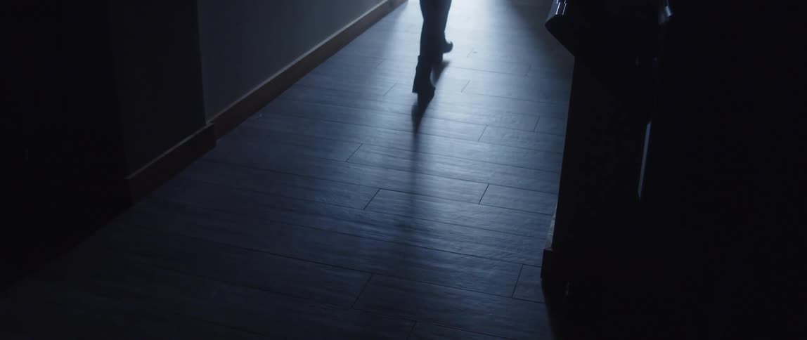 Person walking across floor from dimly lit area to bright area is silhouetted