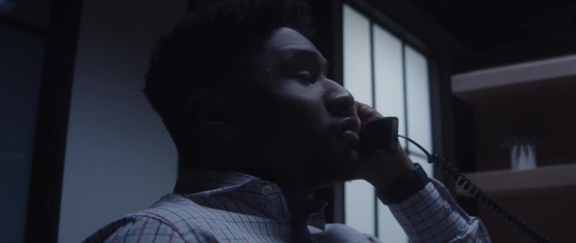 A man in an office yells as he talks on the phone