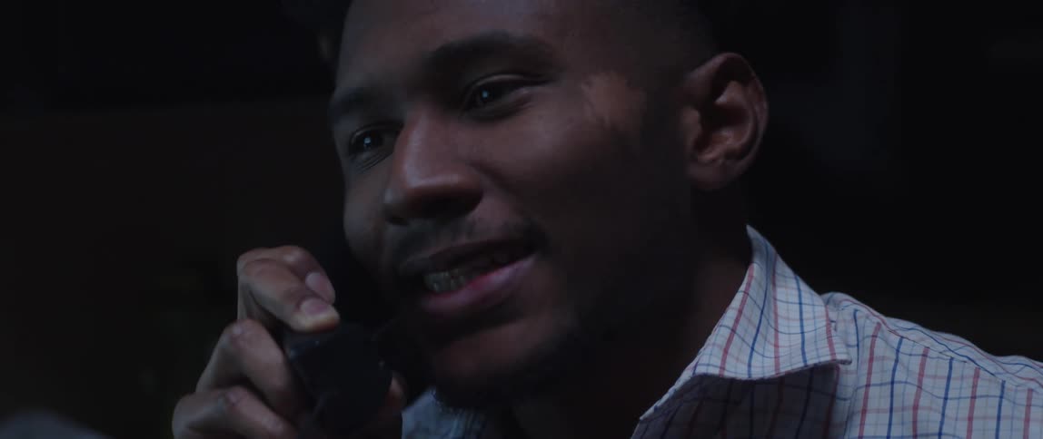 A man talks on a wired phone while sitting indoors