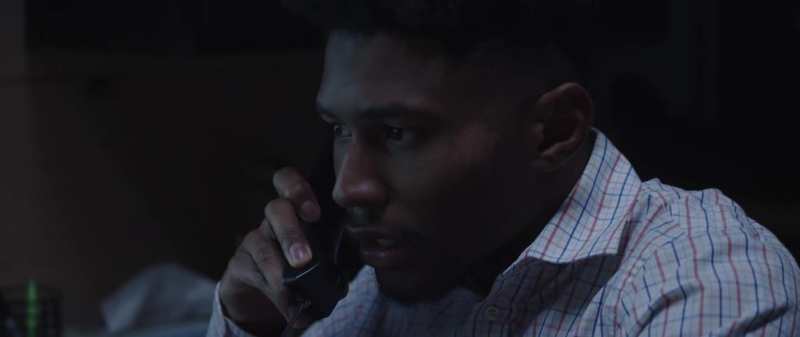 An up close of a mans face while he talks on the phone in the office