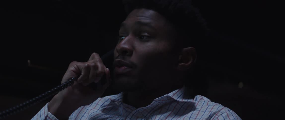 A male employee having a phone conversation in a dark office