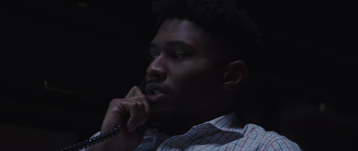 An up close of a man on a corded phone talking and expressing frustration