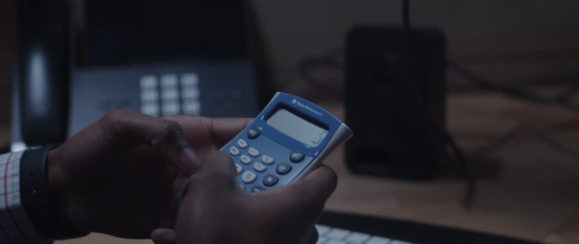 Young man working at the office sitting at his desk uses a calculator