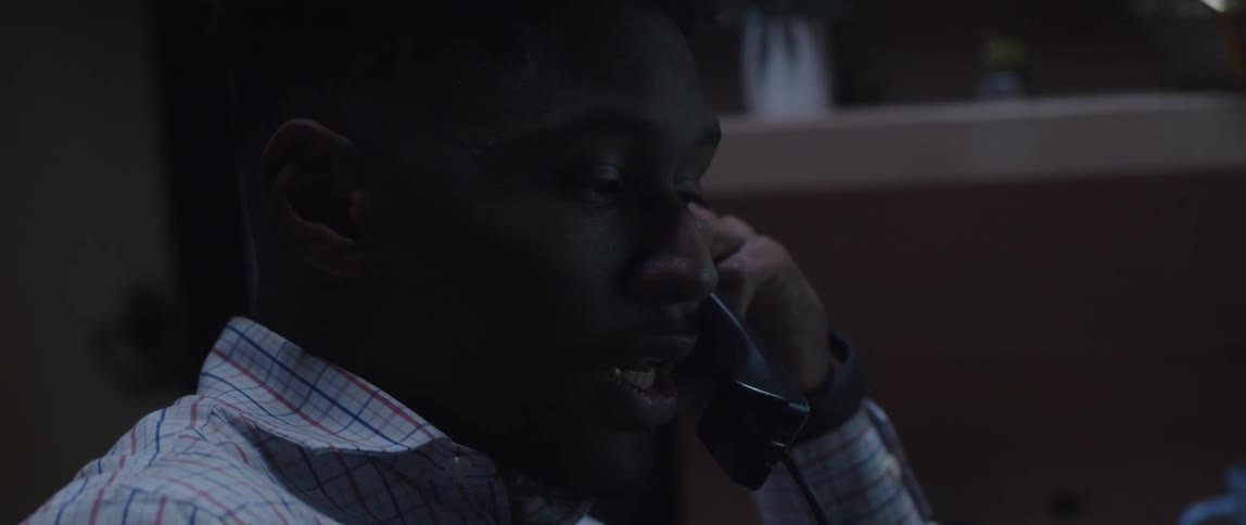 A man talks on a phone while sitting in an office