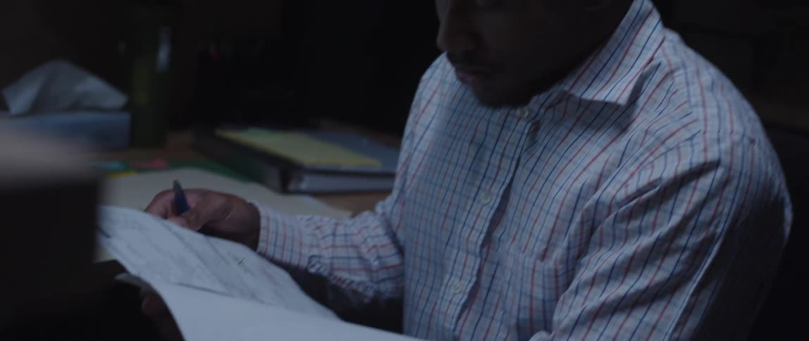 A man in an office flips through papers while sitting at his desk