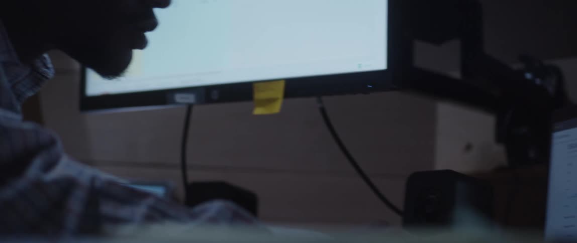 Man working in office leans forward to look at computer screen