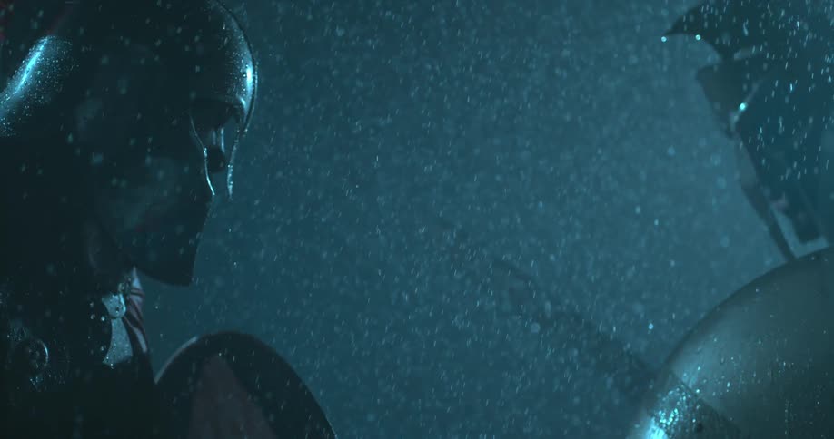 Men facing off each other wearing gladiator gear in the rain