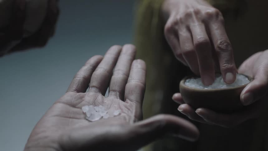 A person puts crystals in another person's hand