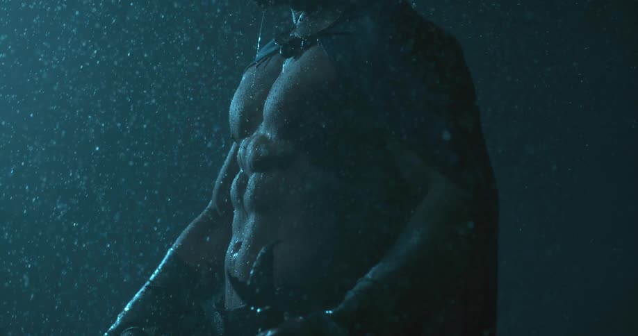 A man is standing out in the rain holding a sword