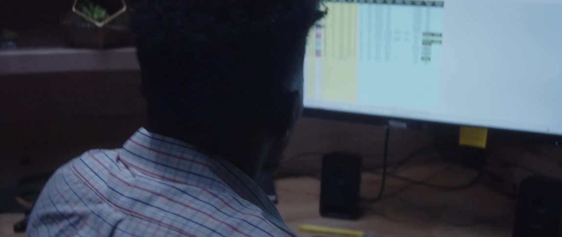A man uses a calculator while working on a spreadsheet at his desk