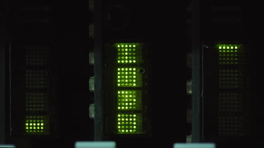 Green lights on a machine move up and down as they glow in the darkness