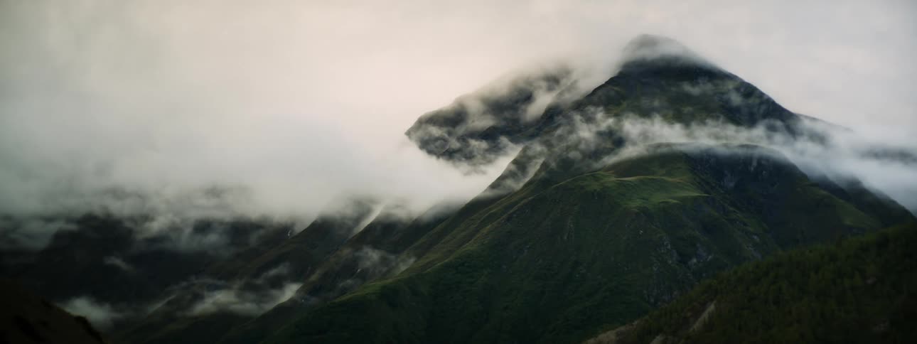 Timelapse of clouds flowing over mountain as seen from a higher location in the daytime