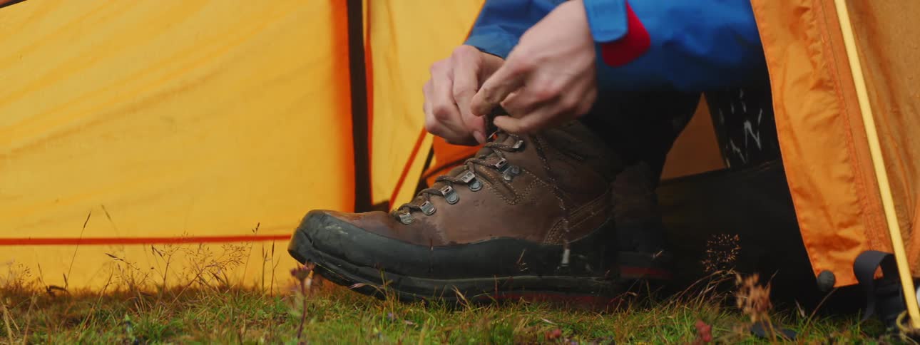 A woman ties her shoe while sitting outside her tent