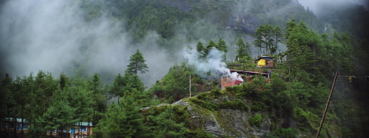 Buildings on mountain slope in the forest with clouds floating