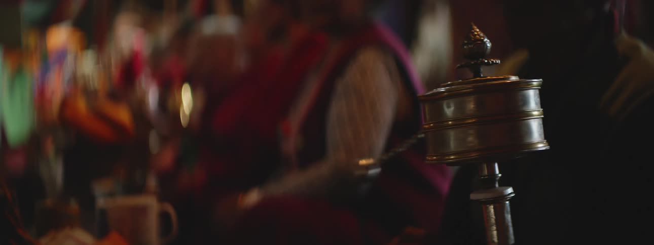 Metal drum with chain and ball rotates on a staff as colorfully dressed people sit at table together