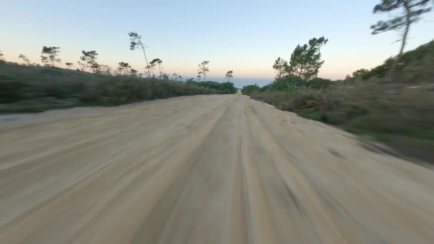 A view of a pathway near a beach is displayed at dusk