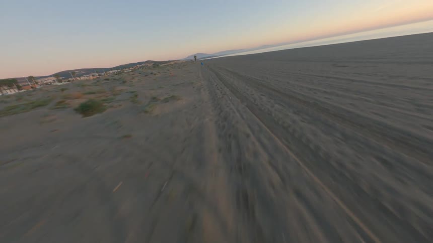 Tire marks run through the beach near the water