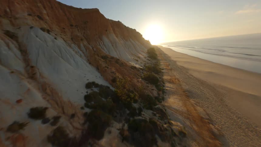 Aerial view of a beach near mountains is displayed