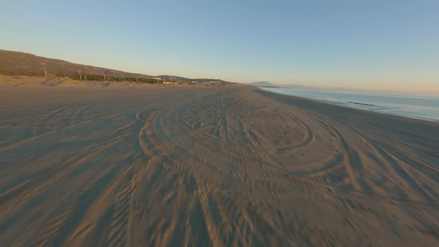 An aerial view of a sandy beach with a lifeguard tower in the morning