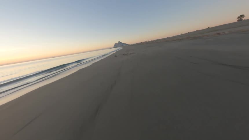 Small shop hut sits on beach a distance from peaks and red horizon
