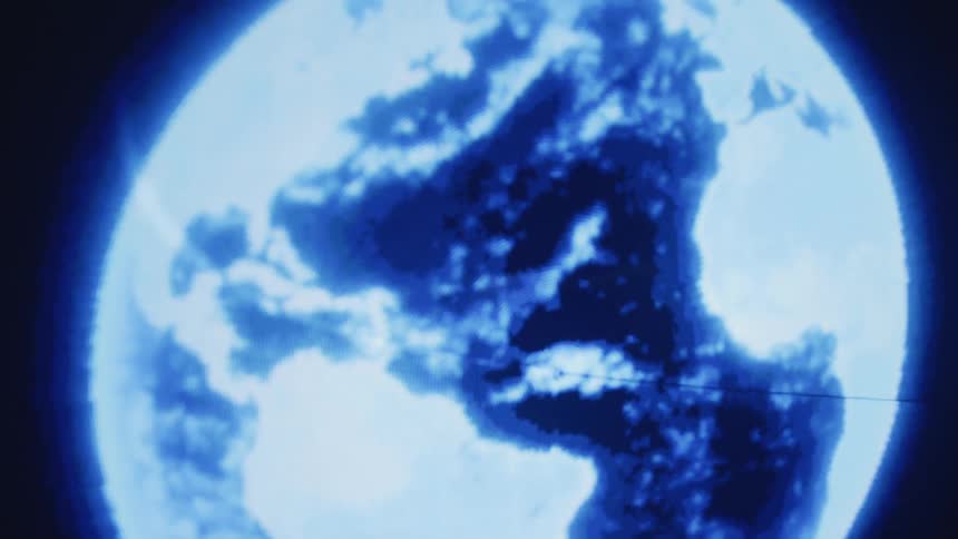 A glowing digital model of planet earth rotates over a table