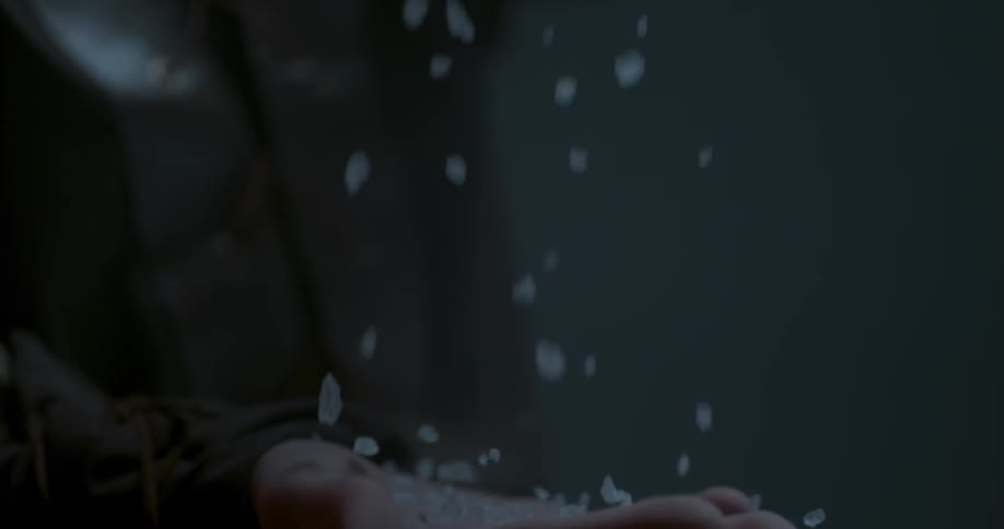 A person is dropping small crystals into his hand