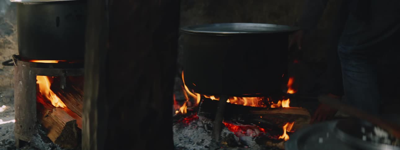 A pot is cooking something on a fireplace