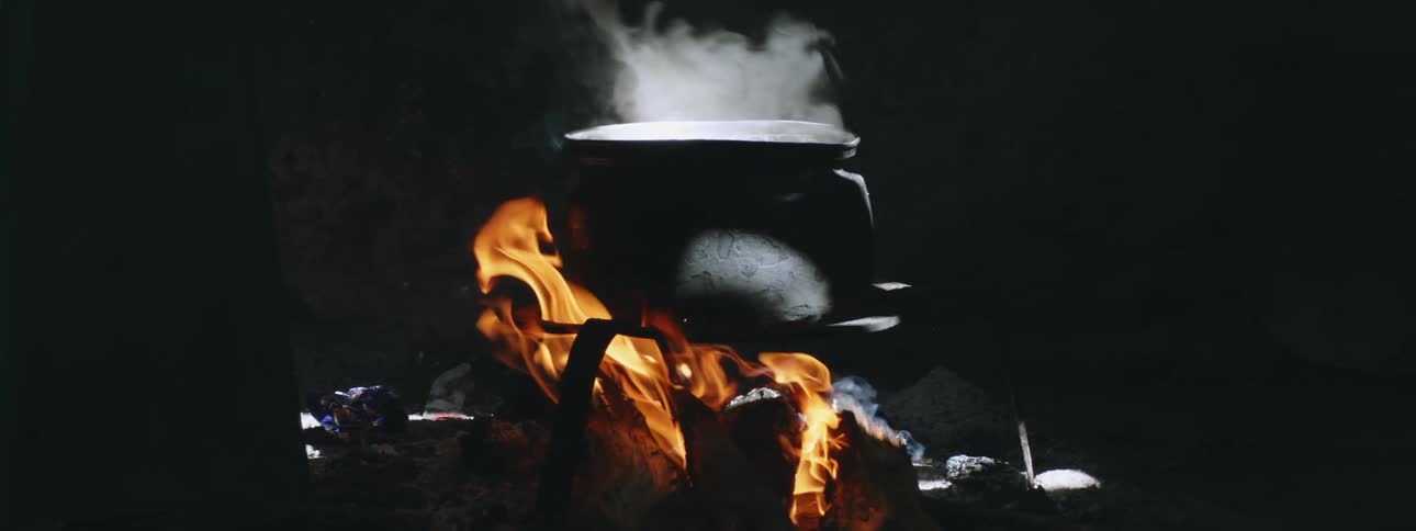 A pot one a fire under wood burning
