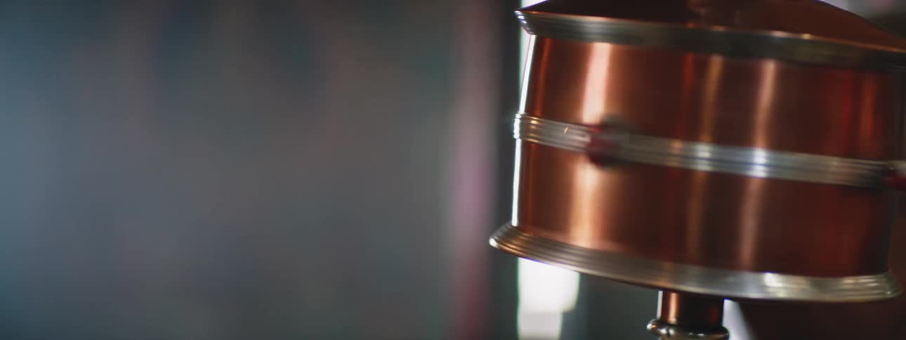 A tibetan prayer wheel is rotating and a person is sitting nearby