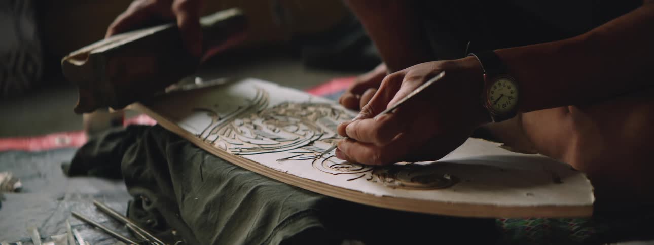 Close up of the hands of an artisan carving with a chisel by hand