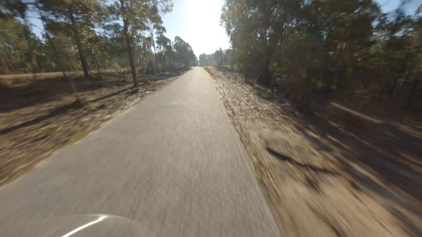 Drone passing by a car and moving down the road at a high rate of speed