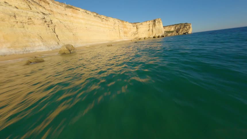 Aerial view of an ocean near a cliff is displayed