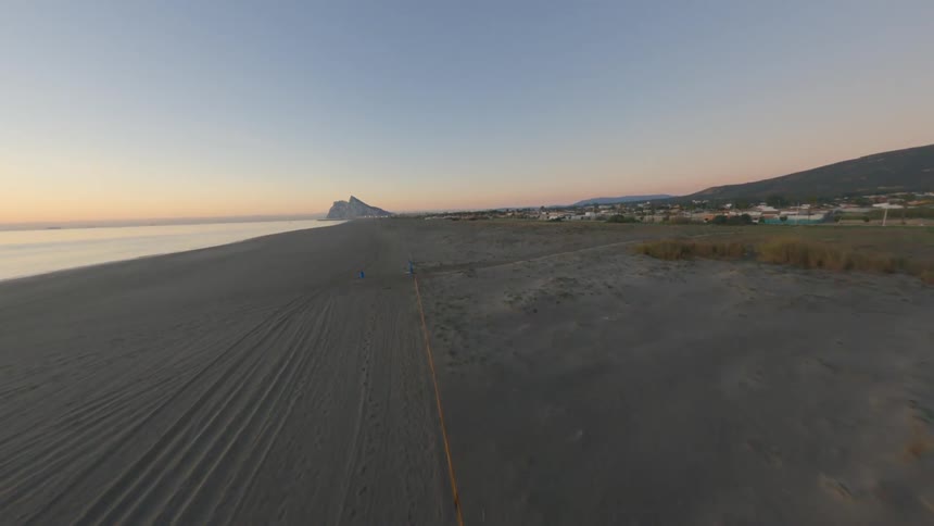 Aerial footage from a drone racing along an empty beach in the morning