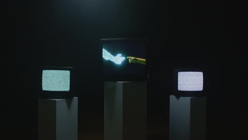 Three televisions displayed on pillars in a dark room