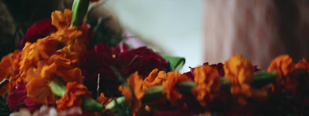 Close up of vibrant yellow flowers being threaded into a wheath by an artisan
