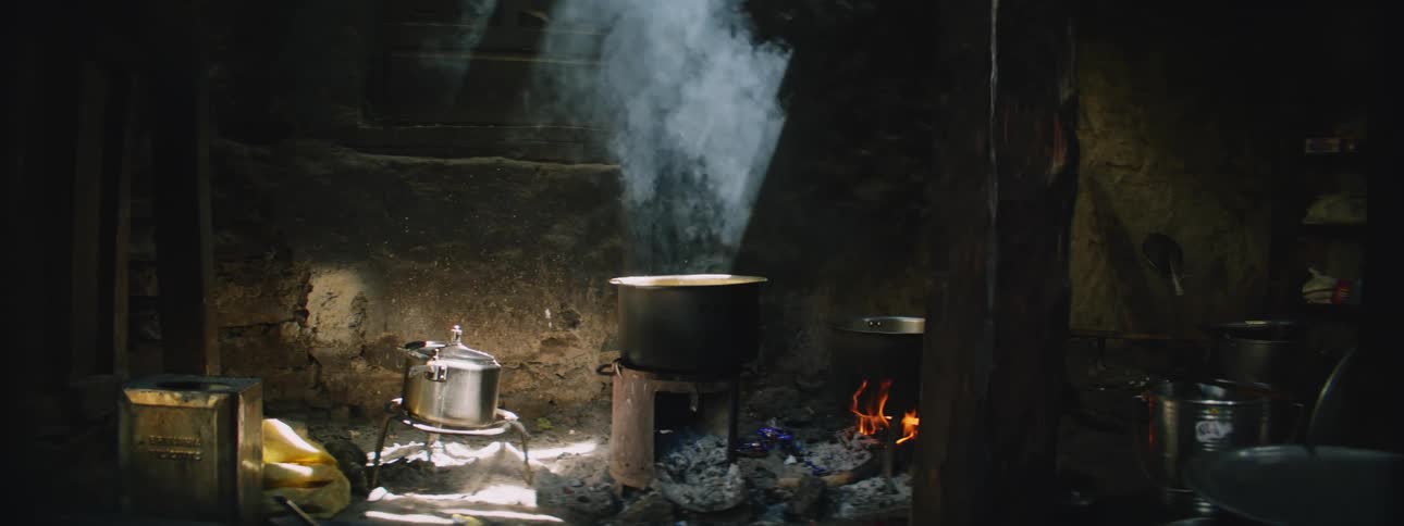 A pot of food cooking over an open fire in an old shack