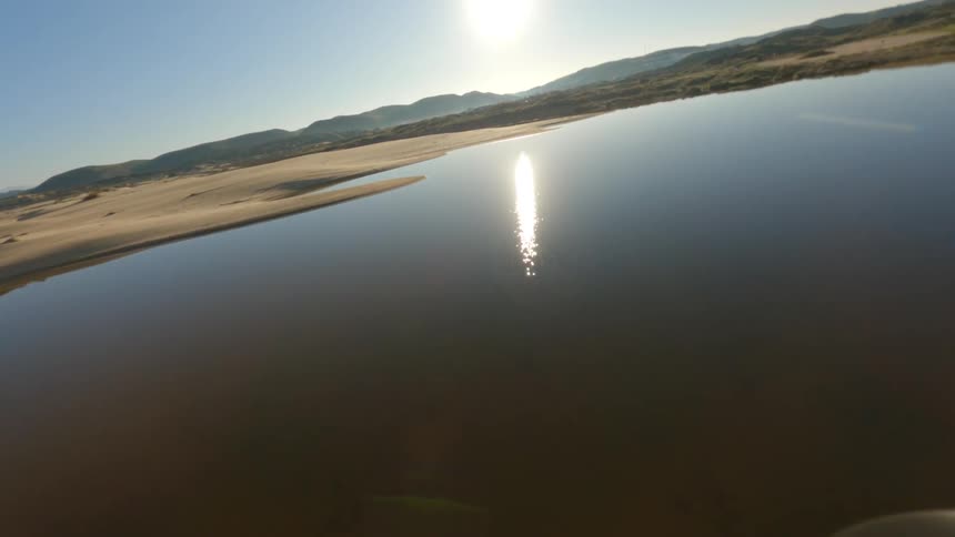 Dynamic drone footage flying close to the coastline of lakes in the hills at morning