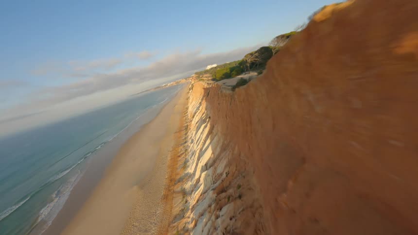 People move along narrow beach between cliffs and ocean