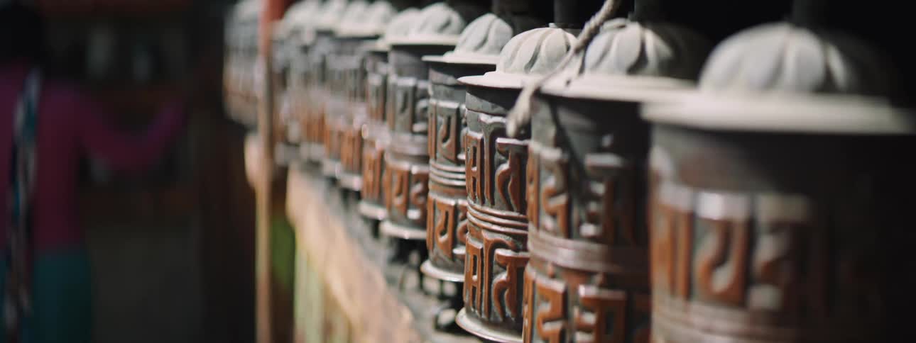 An elderly person running their hands along rotating carved decorations