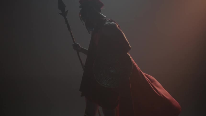 A man wears a cape and carries a spear