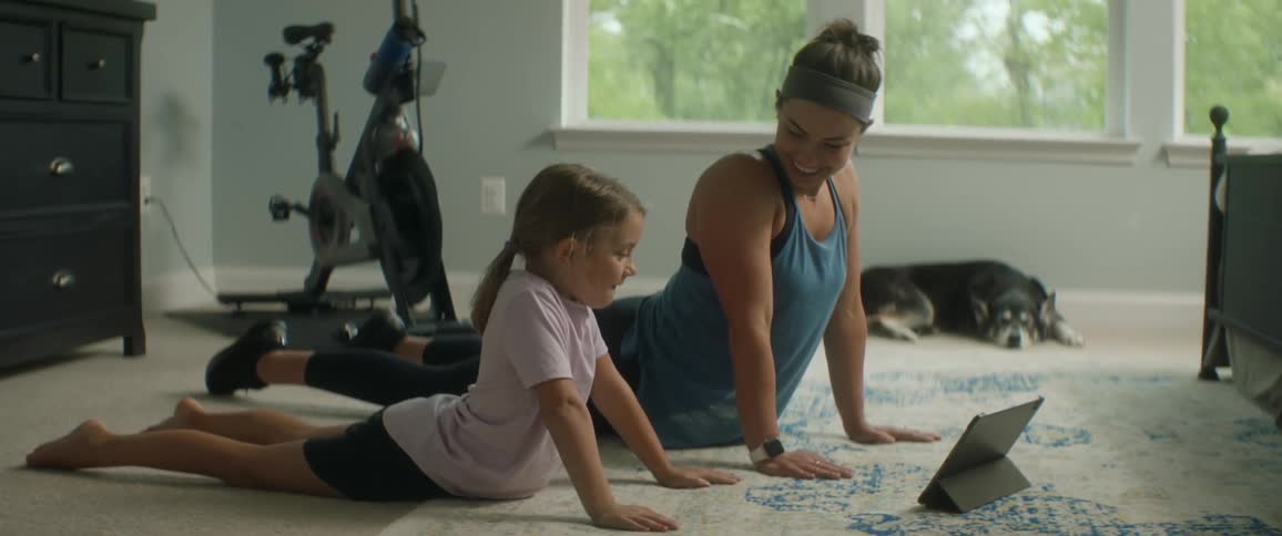 A woman and daughter stretch upwards from the floor in a yoga pose