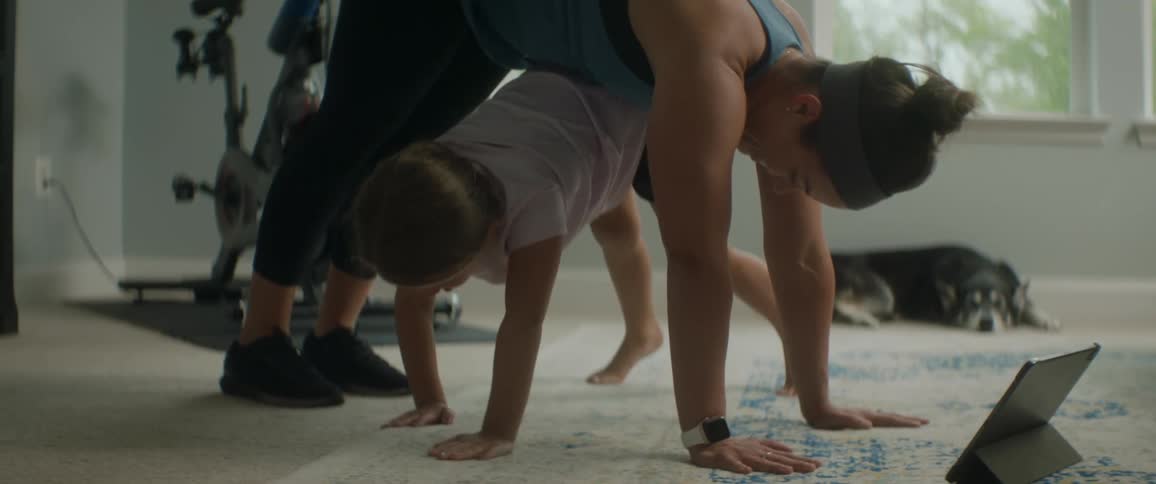 A child crawls under a woman while she is completing a yoga pose