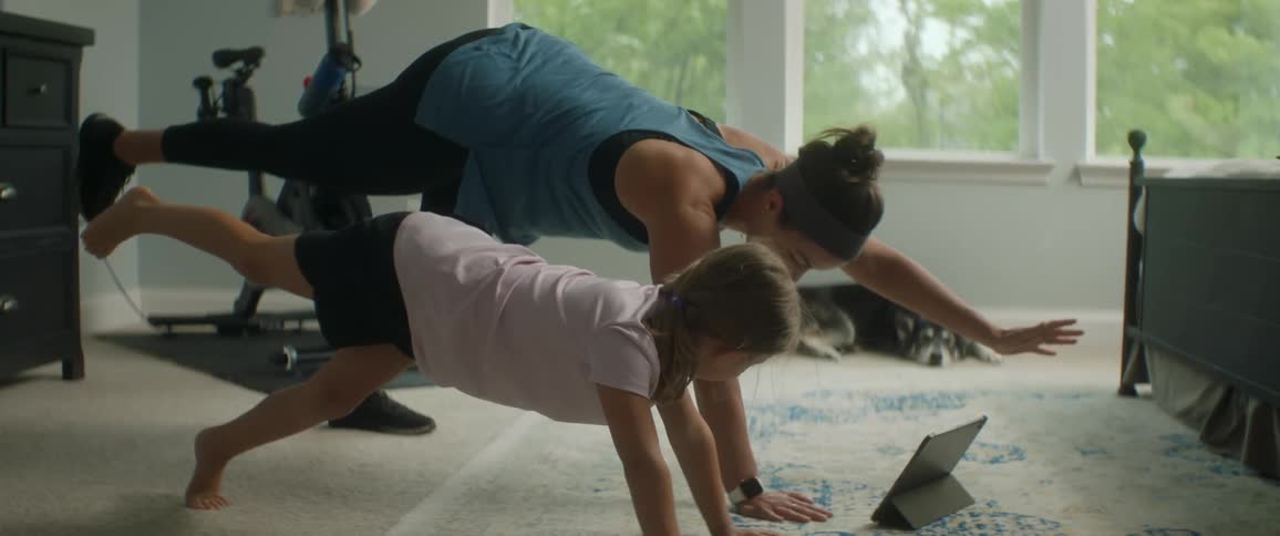 A woman and child perform poses in front of a tablet