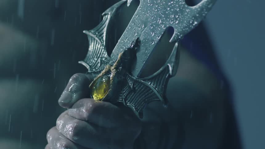 A man is holding a sword in the rain