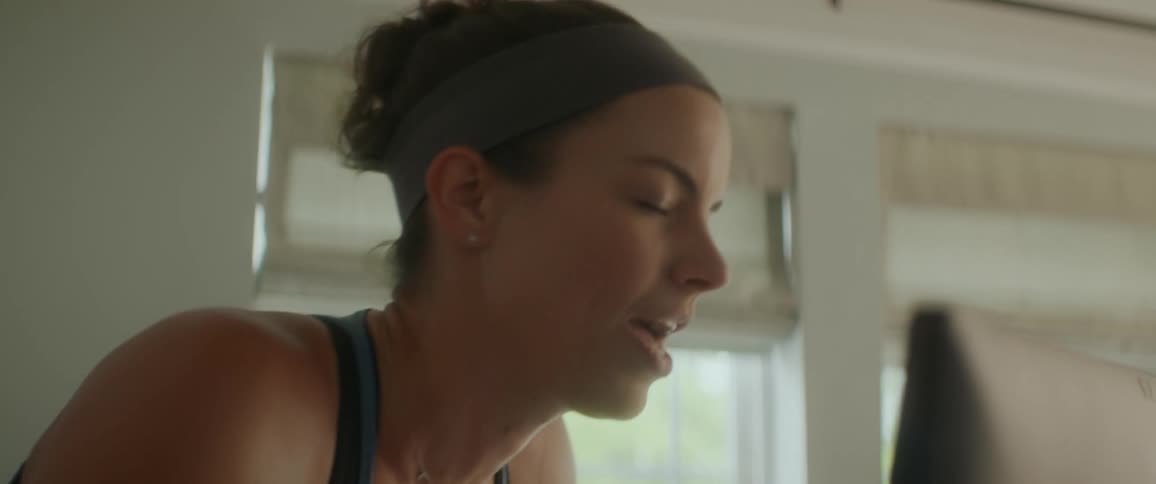 A woman smiles while using a fitness bicycle indoors