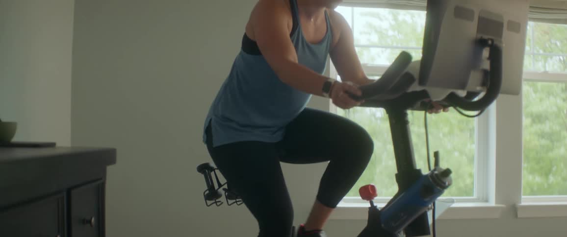 A woman is using an exercise bike indoors