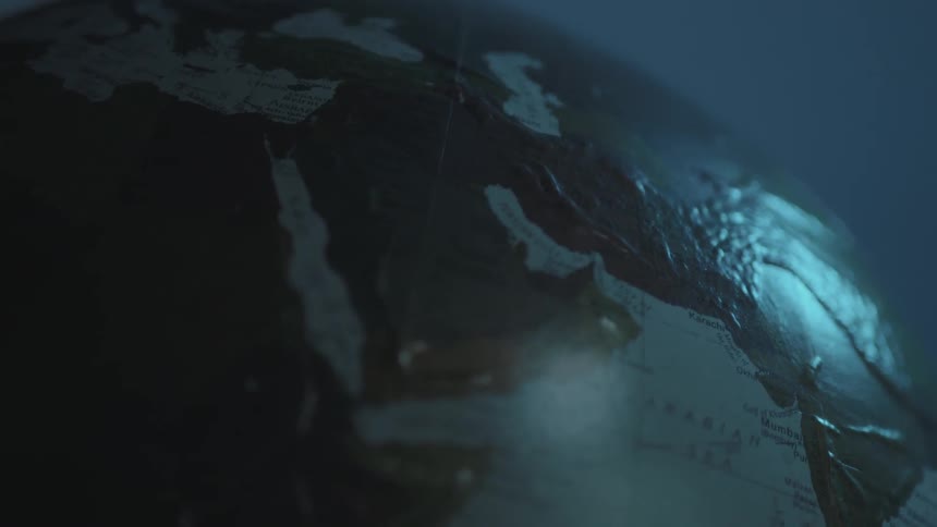 A world globe sits in a dark room
